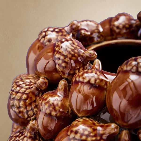 Gros plan sur les glands sculptés et la finition brillante du vase brun en grès