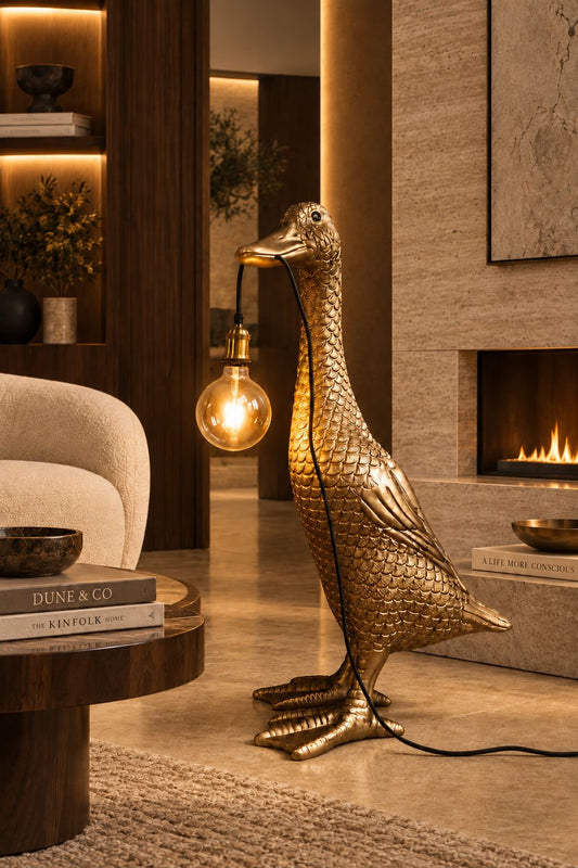 Lampadaire Ducky doré DUNE & CO avec ampoule suspendue, présenté dans un intérieur élégant aux tons chauds, pierre et bois