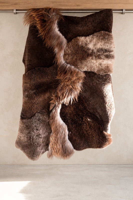 Tapis Mélangé brun chiné en peau de mouton naturelle présenté suspendu, vue complète du patchwork et des textures